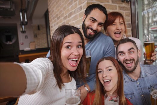 Group of happy people taking selfies while drinking beer together. Friendship, celebration concept