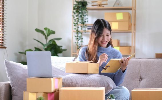 Startup small business owner working with computer at workplace. Freelance two woman seller check product order. Packing goods for delivery to customer. Online selling. E-commerce. Shipping concept.