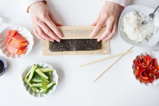 Sushi preparation process, the girl makes sushi with different flavors - fresh salmon, caviar, avocado, cucumber, ginger, rice