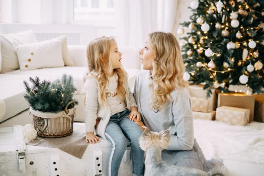 Happy family: mother and daughter. Family in a bright New Year's interior with a Christmas tree.