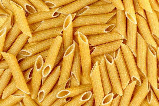 Raw whole grains pasta penne rigate cooking pasta. Selective focus. Cooking homemade food. Texture