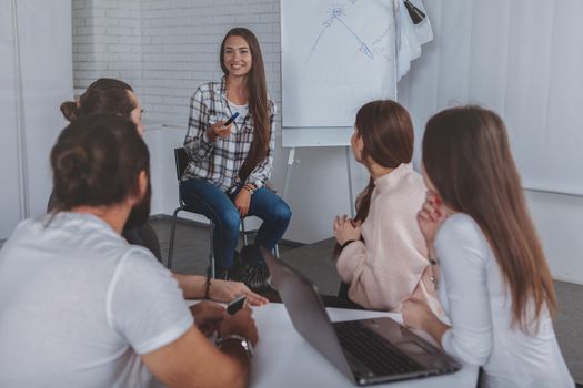 Attractive businesswoman enjoying talking to her colleagues, leading brainstorming meeting at her office. Group of businesspeople working on a project together
