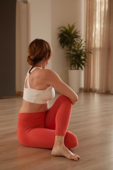Vertical shot of a woman doing core twisting asana, procticing yoga