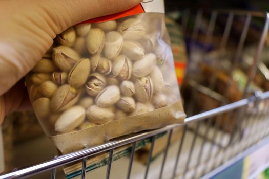 Pre packaged snacks pistachios nuts on the shelves of the hypermarket. Selective focus