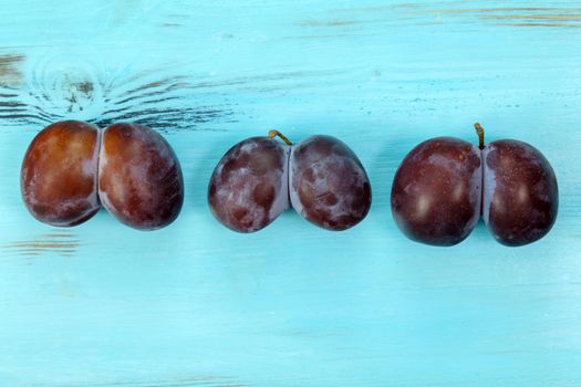 Trendy ugly food concept. Plums on blue background. Fruit with a strange shape. The problem of food waste.