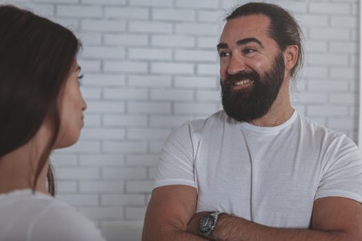 Charming mature businessman laughing, talking to female colleague at work. Happy bearded man enjoying working with his female friend. Two colleagues talking. Partnership, communication concept
