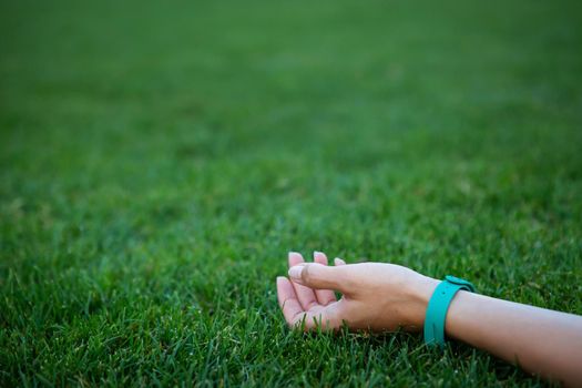 The girl lies on the grass, her hand is on a freshly mown smooth green lawn, relaxes in the open air. Background, place for an inscription