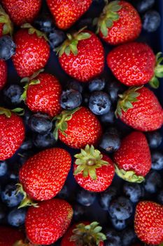 Background of assorted fresh berries of red juicy strawberries and blue blueberries close-up. View from above