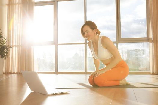 Cheerful mature woman using laptop, doing online yoga class, copy space