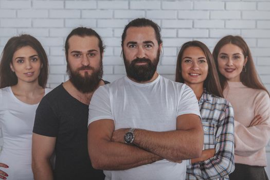 Handsome bearded mature businessman smiling to the camera, posing confidently with his successful creative businessteam a the office. Leadership, entrepreneurship concept