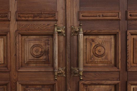 Antique massive wooden doors with large handles close-up. Ancient architecture.