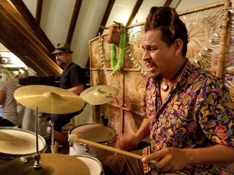 Honolulu - August 19, 2017: Musicians Jerome James playing drum instruments on stage with Roxotica band Ward Rafters in Honolulu, Hawaii.