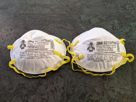 Honolulu - August 1, 2020: Two White N95 Face Masks with yellow ear straps made by 3M on floor.