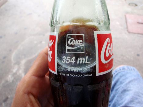 San Jose, Costa Rica - July 13, 2009: Close-up of Hand holding 
glass Coke Bottle 354ml made in 1995.