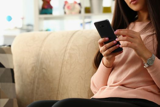 Woman using smartphone sitting on sofa at home. Communication in social networks using Internet and online shopping