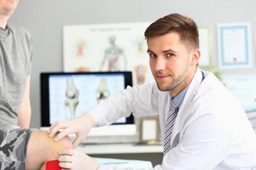 Doctor orthopedist treatment of knee joint with kinesio tapes. Diagnosis and prevention of knee injuries