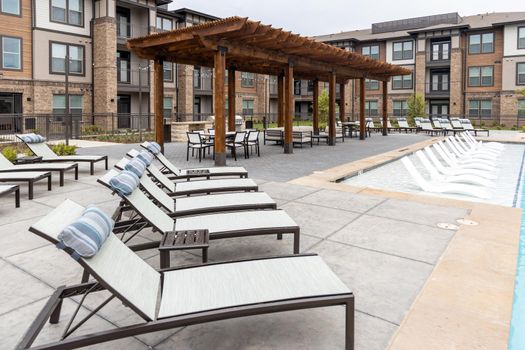Deck chairs in the backyard of the residential complex, recreation zone and rooftop dining area with building on background