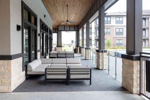 Decorative terrace with view outside of modern residential complex, sitting area with sofas and armchairs. Architecture and relaxation