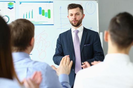 Male business coach speaker in suit makes presentation. Speaker leader advises on training persuading the employees of client group