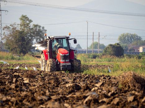 farmer with tractor plowing the land in the countryside.