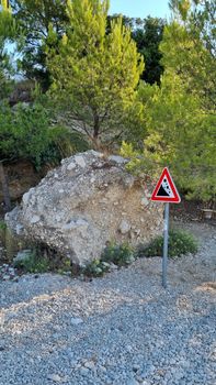 Attention sign for rock fall. Attention sign Falling rocks. Biokovo Mountain Nature park and trees from Makarska Riviera-Biokovo, Dalmatia, Croatia, Europe.