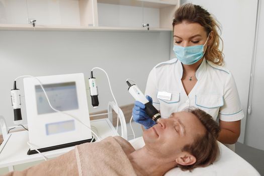 Professional cosmetologist working during pandemic, wearing medical face mask at her beauty clinic