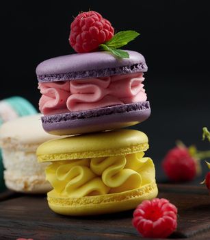 A stack of multi-colored macaroons on a wooden board. Delicious dessert