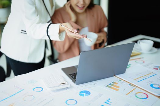 A portrait of two female employees using computers while working to analyze their finances and increase their marketing strategies to combat their competitors.