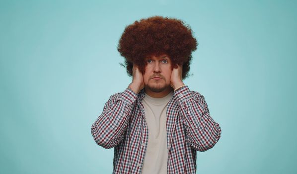 Dont want to hear and listen. Frustrated annoyed irritated man covering ears and gesturing no, avoiding advice ignoring unpleasant noise loud voices. Young guy isolated on blue studio wall background