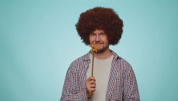 Magician wizard man gesturing with magic wand fairy stick, making wish come true, casting magician spell, advertising holidays sale discount. Young adult guy boy isolated on blue studio background