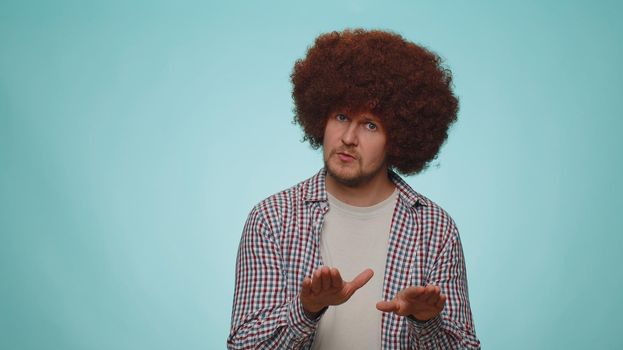 Hey you, be careful. Man warning with admonishing finger gesture, saying no, be careful, scolding and giving advice to avoid danger, disapproval sign. Young guy isolated on blue studio wall background