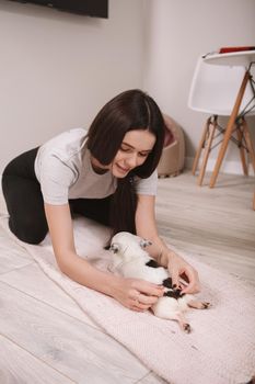 Vertical shot of a beautiful woman lying on the rug with her small chihuahua dog