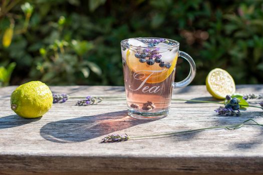 cold refreshing tea with blueberry, lime and lavender on a hot summer day on a wooden table. High quality photo