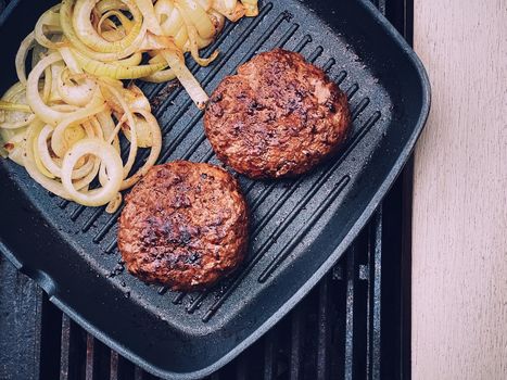 Cooking minced beef burger on cast iron grill skillet outdoors, red meat on frying pan, grilling food in the garden, English countryside living concept