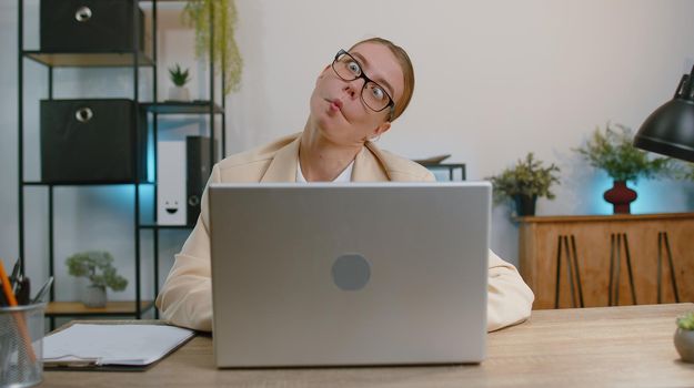 Business woman hiding behind laptop computer, making funny face, fooling around, putting his tongue out remote working disrespecting someone at home office. Freelancer business girl busy occupation