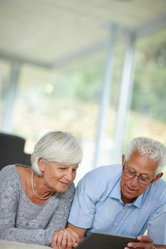 Add a little technology to your day. a senior couple lying on the floor while using a digital tablet