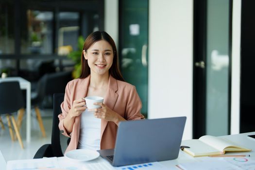 Portrait of a woman taking a coffee break while using a computer