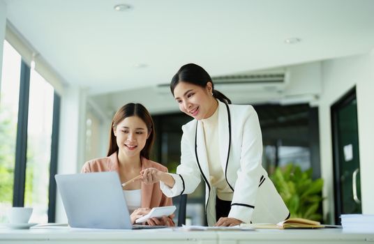 A portrait of two beautiful female employees discussing how they use computers to plan their marketing goals.