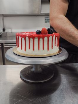 hand pof chef making for icing a red drip cake in the professional kitchen lab