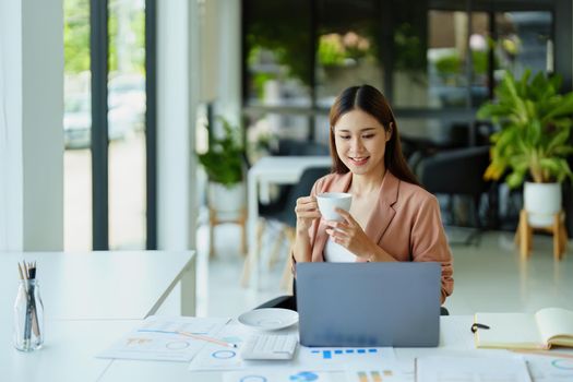 Portrait of a woman taking a coffee break while using a computer