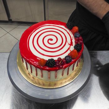 hand pof chef making for icing a red drip cake in the professional kitchen lab