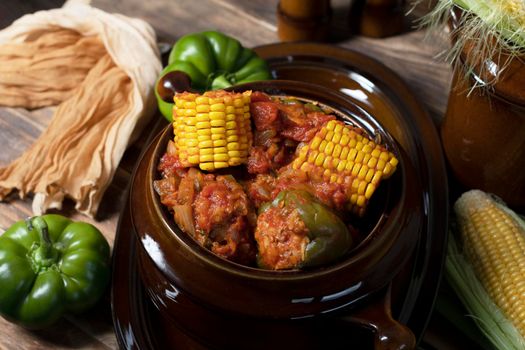 stuffed bell peppers with corn on the cob stewed in tomatoes, still life on wooden boards, traditional autumn dishes. High quality photo
