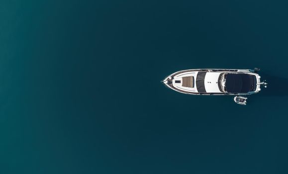 Aerial boat race. Luxury cruise trip. View from above of white boat on deep blue water. Aerial view of rich yacht sailing sea. Motor boat racing wave. Summer journey on luxury ship