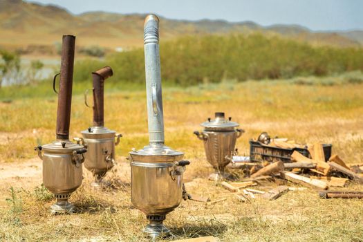 Boiling samovar in the steppe with fire wood. Catering travel outdoor.