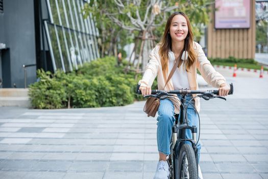 Happy Asian beautiful young woman riding bicycle on street outdoor near building city, Portrait of smiling female lifestyle using bike in summer travel means of transportation, ECO friendly