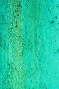 A wall with beautiful blue-green smudges, stripes. Texture from a scratched surface with green paint damaged by time.