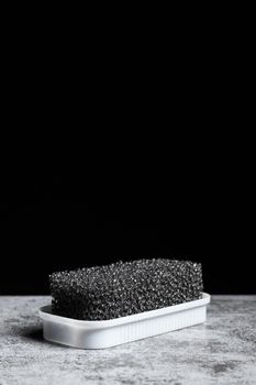 Foam sponge for suede shoes on a black background with copy space vertical.