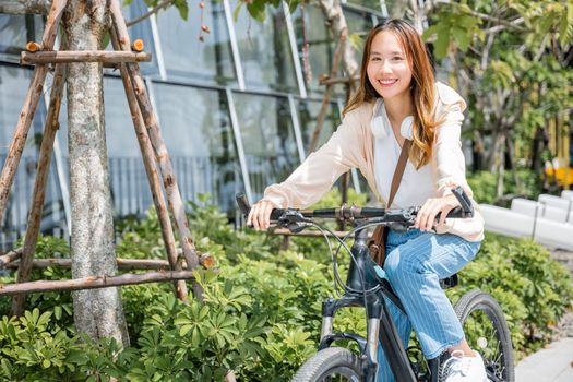 Happy Asian beautiful young woman riding bicycle on street outdoor near building city, Portrait of smiling female lifestyle using bike in summer travel means of transportation, ECO friendly