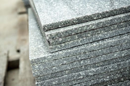 Close-up on grey polished stone tiles piled on top of each other.