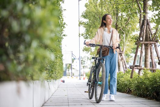 Happy female smiling walk down the street with her bike on city road, ECO environment, healthy holiday travel, Asian young woman walking alongside with bicycle on summer in park countryside outdoor